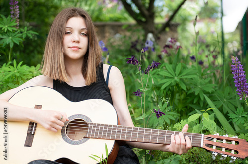 Teenager girl playing guitar in park