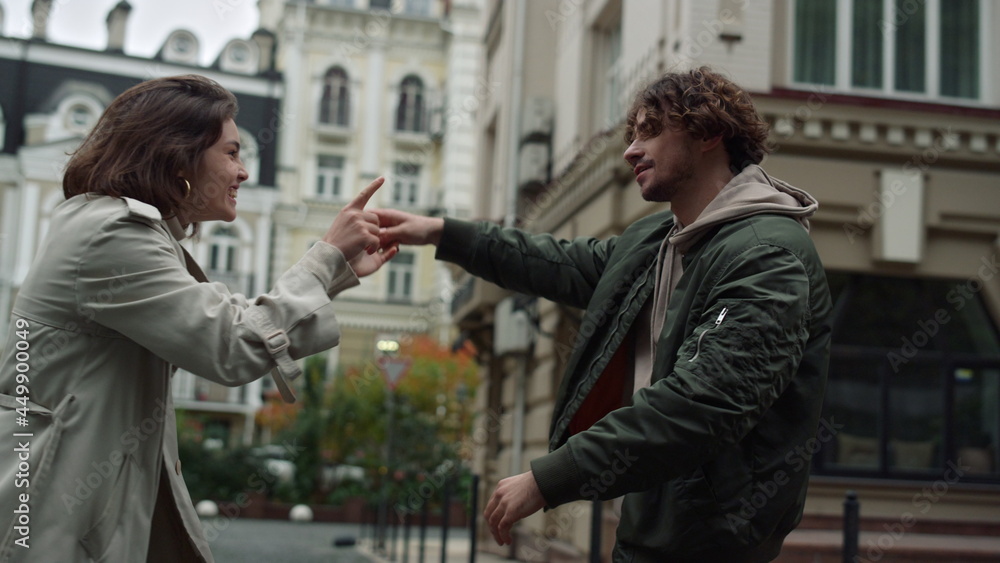 Cheerful couple having fun outside. Woman and man dancing on urban street. Cheerful couple having fun outside. Woman and man dancing on urban street.