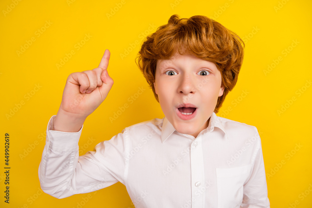Photo of young funky smiling good mood boy point finger up find idea solution genius isolated on yellow color background Photo of young funky smiling good mood boy point finger up find idea solution genius isolated on yellow color background