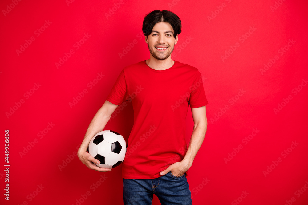 Photo of young sportive man happy positive smile hold soccer ball play football game isolated over red color background Photo of young sportive man happy positive smile hold soccer ball play football game isolated over red color background