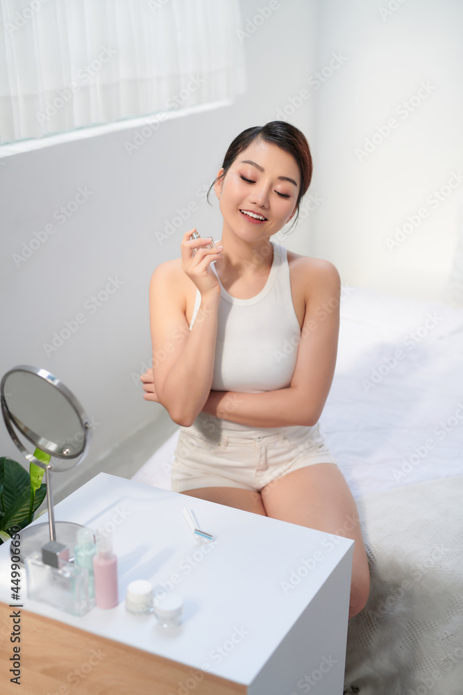 Young smiling woman enjoying her morning while applying favorite perfume Young smiling woman enjoying her morning while applying favorite perfume