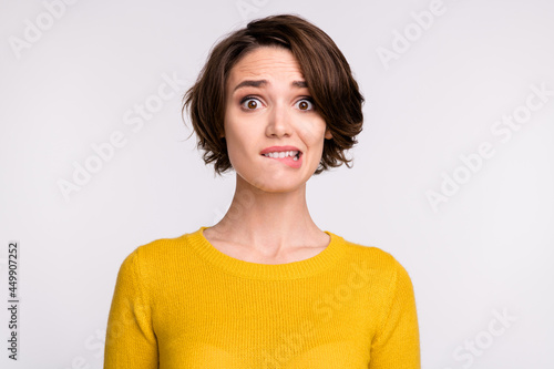Photo of nervous scared frightened girl look camera bite lips wear yellow shirt isolated grey color background
