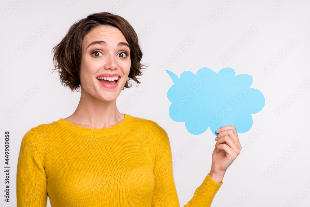 Photo of young woman happy positive smile hold paper bubble speak talk ad information isolated over grey color background Photo of young woman happy positive smile hold paper bubble speak talk ad information isolated over grey color background