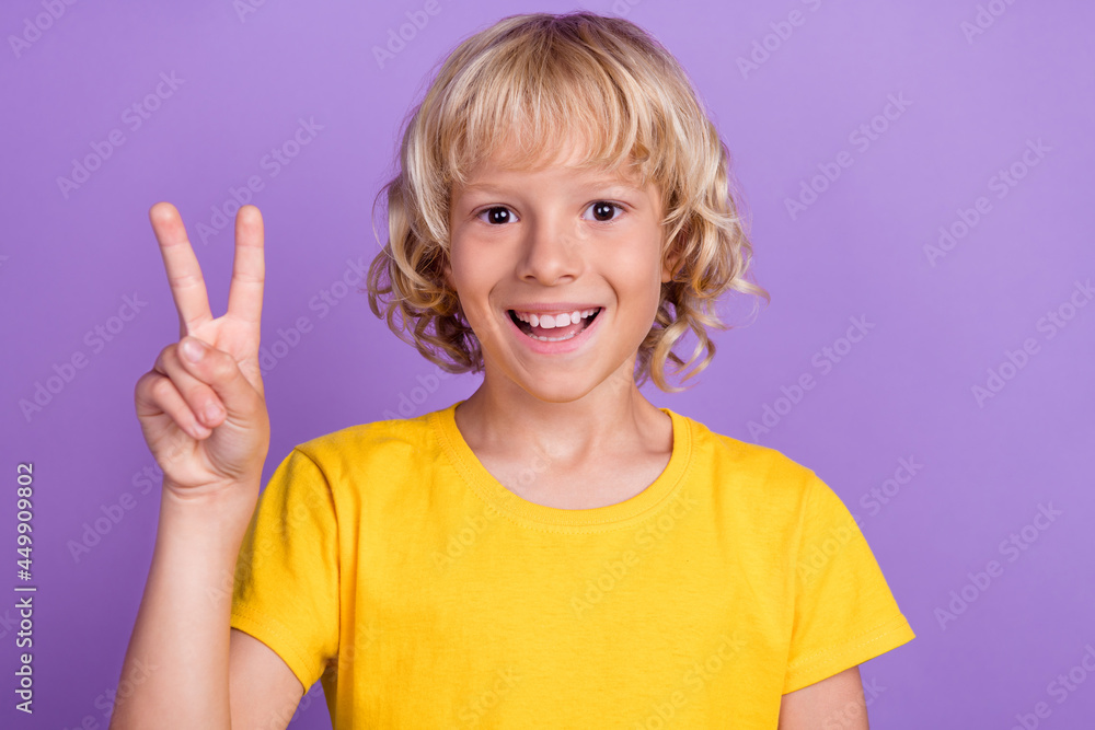 Photo of funny excited friendly boy show v-sign wear yellow t-shirt isolated purple color background Photo of funny excited friendly boy show v-sign wear yellow t-shirt isolated purple color background