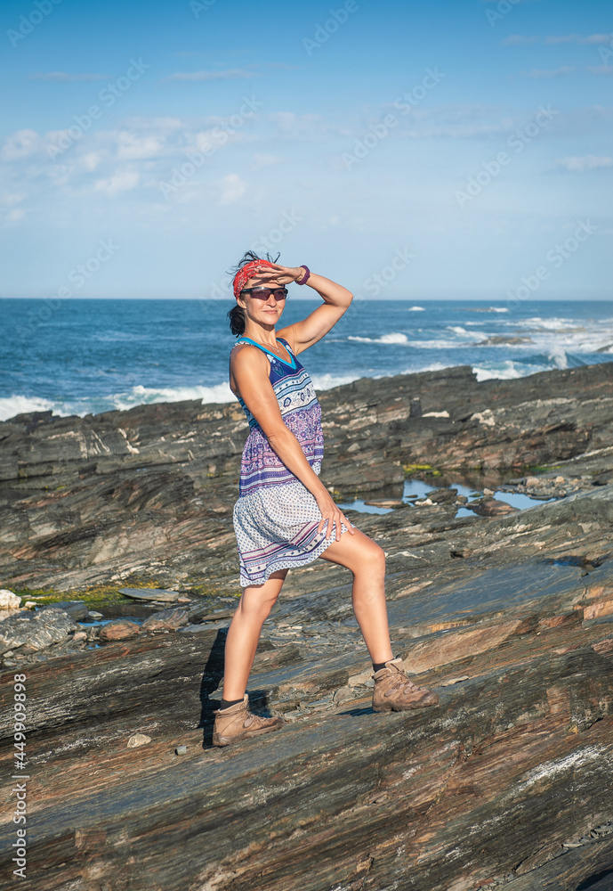 Beautiful woman in dress standing on boulders of rock against sea waves. Beautiful woman in dress standing on boulders of rock against sea waves.