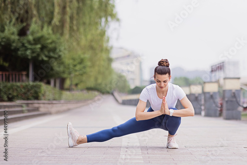 Portrait of happy young caucasian woman exercising yoga outdoors early morning. Beautiful girl practicing asana in park at summer © Алина Бузунова