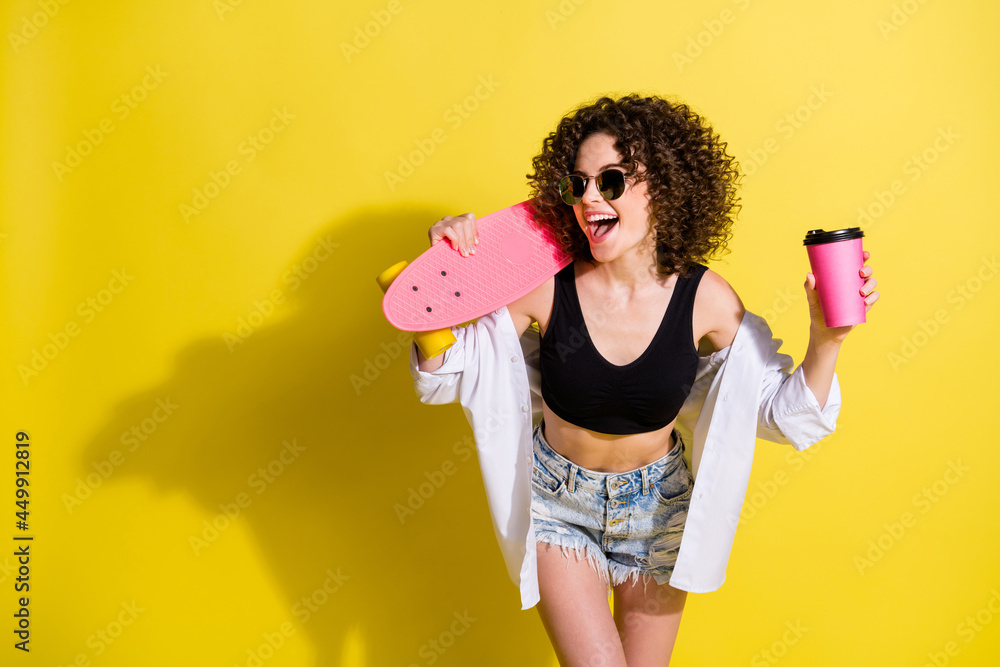 Photo portrait of young girl with skateboard wearing sunglass keeping coffee looking blank space isolated on vibrant color background Photo portrait of young girl with skateboard wearing sunglass keeping coffee looking blank space isolated on vibrant color background