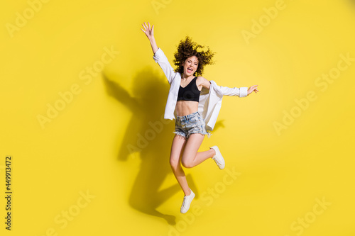 Full size photo of optimistic nice girl jump wear black top shorts sneakers isolated on yellow background