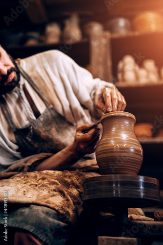 The potter professionally forms the shape of a bowl on a potter wheel from a damp piece of clay photo