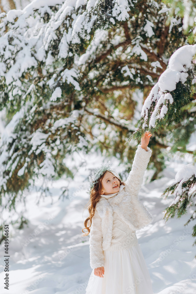 Little girl shaking the branch of pine tree covered by snow. Little girl shaking the branch of pine tree covered by snow.