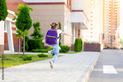 a child schoolgirl with a backpack jumps with happiness and runs to school on the first day of autumn, the concept of back to school, rear view © Any Grant