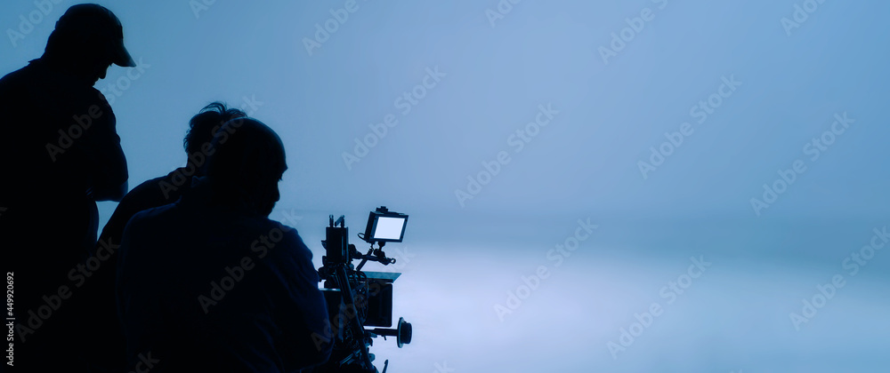 Video production behind the scenes. Making of TV commercial movie that film crew team lightman and cameraman working together with film director in studio. film production concept. Silhouette style.