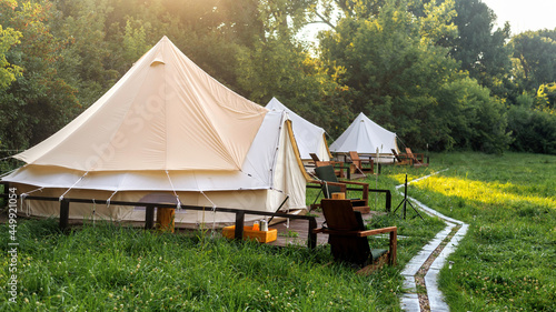 Glamping, few tents, chairs and pathway on the foreground