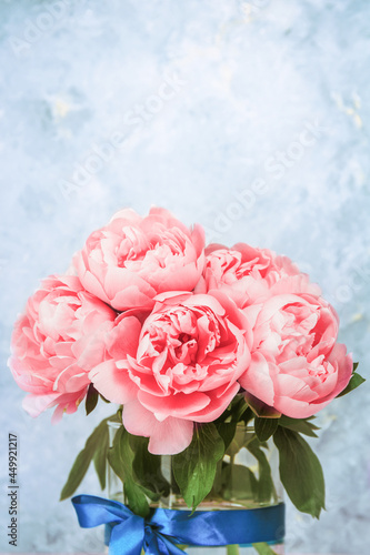 Artistic floral background. Beautiful pink peonies flowers bouquet in a glass vase. Large buds of pink peonies