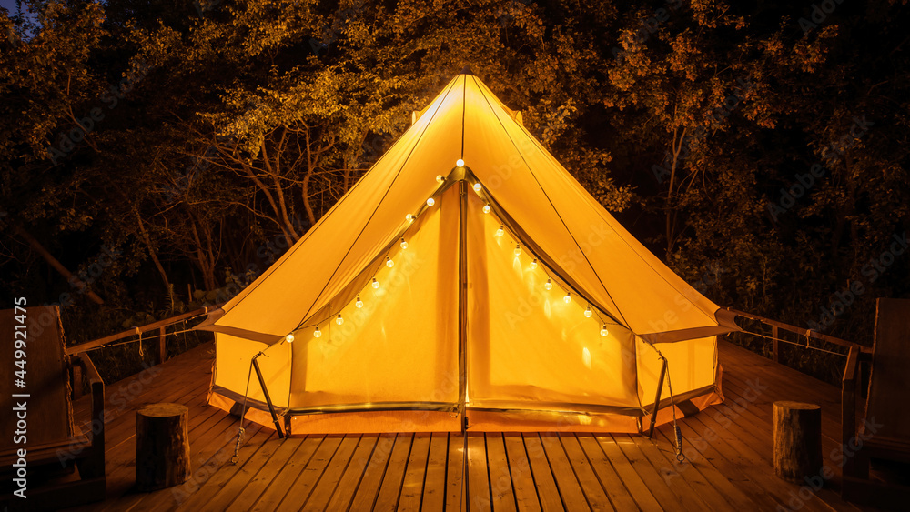 Glamping at night, glowing tent with chairs in front of it
