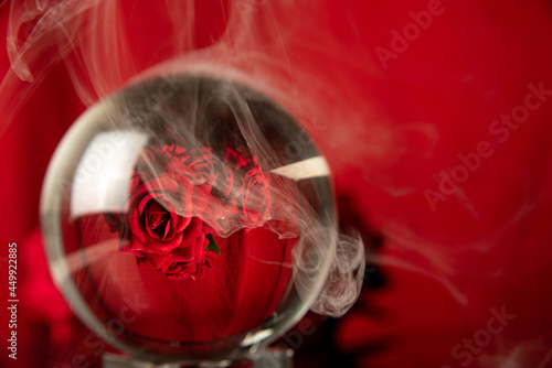 crystal ball reflecting a bouquet of red roses and smoke, selective focus.
