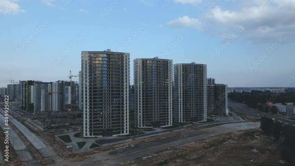 Construction of a modern city block. Multi-storey buildings and elements of urban infrastructure. Construction work and finishing of buildings are in progress. Aerial photography at dusk at sunset.