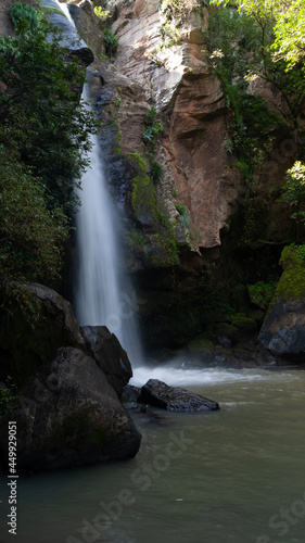 cascada de agua callendo hacia laguna entre rocas y vegetación photo