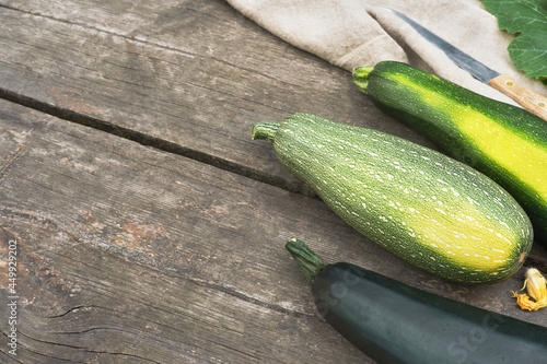 Locally grown vegetables and sustainable, climate friendly eating concept. Organic, green zucchini with textile napkin on a wooden background with place for text