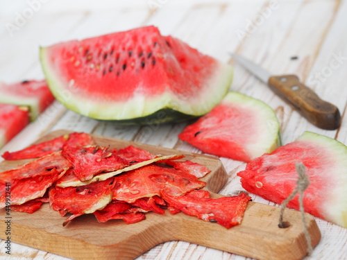 Dried and fresh slices of watermelon on a kitchen board on a wooden white table.