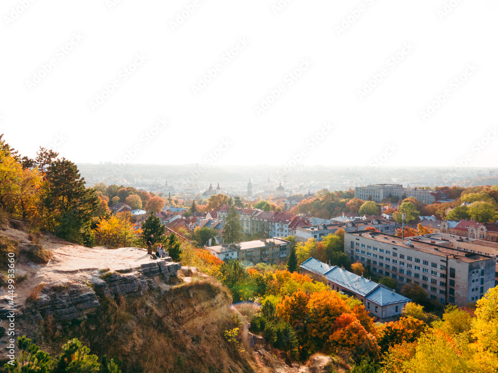 Lviv, Ukraine - October 27, 2020: friends sitting on the cliff enjoying view of autumn city