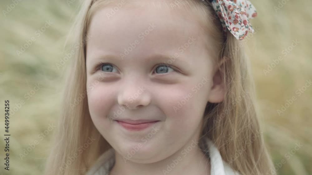 Headshot portrait of charming pretty little girl laughing looking at camera and looking around. Close-up face of happy carefree Caucasian child resting outdoors on autumn field meadow posing Headshot portrait of charming pretty little girl laughing looking at camera and looking around. Close-up face of happy carefree Caucasian child resting outdoors on autumn field meadow posing