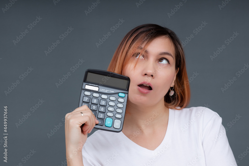 Portrait of a serious female accountant holding a calculator on a gray background. Portrait of a serious female accountant holding a calculator on a gray background.