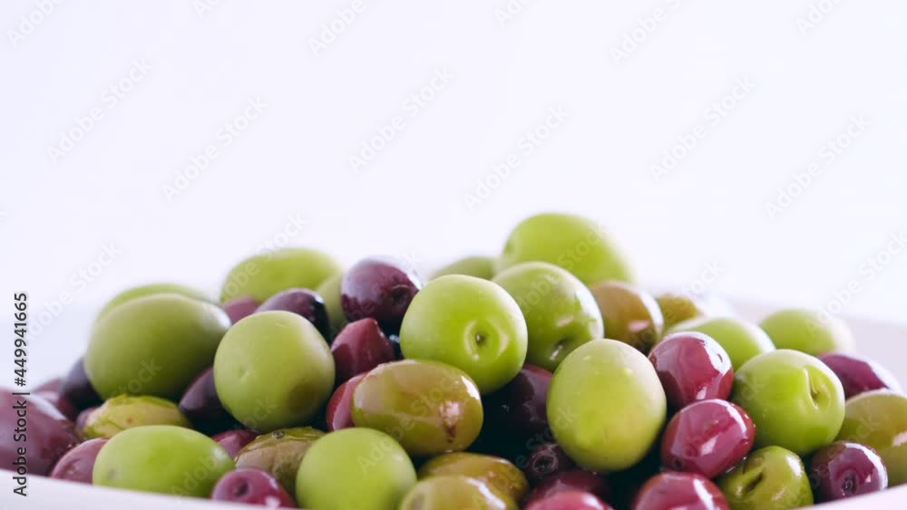 Olives in olive oil spin around themselves on white background. Rotating shot. Mediterranean organic fresh healthy food ingredient, slow motion, close up, macro Olives in olive oil spin around themselves on white background. Rotating shot. Mediterranean organic fresh healthy food ingredient, slow motion, close up, macro