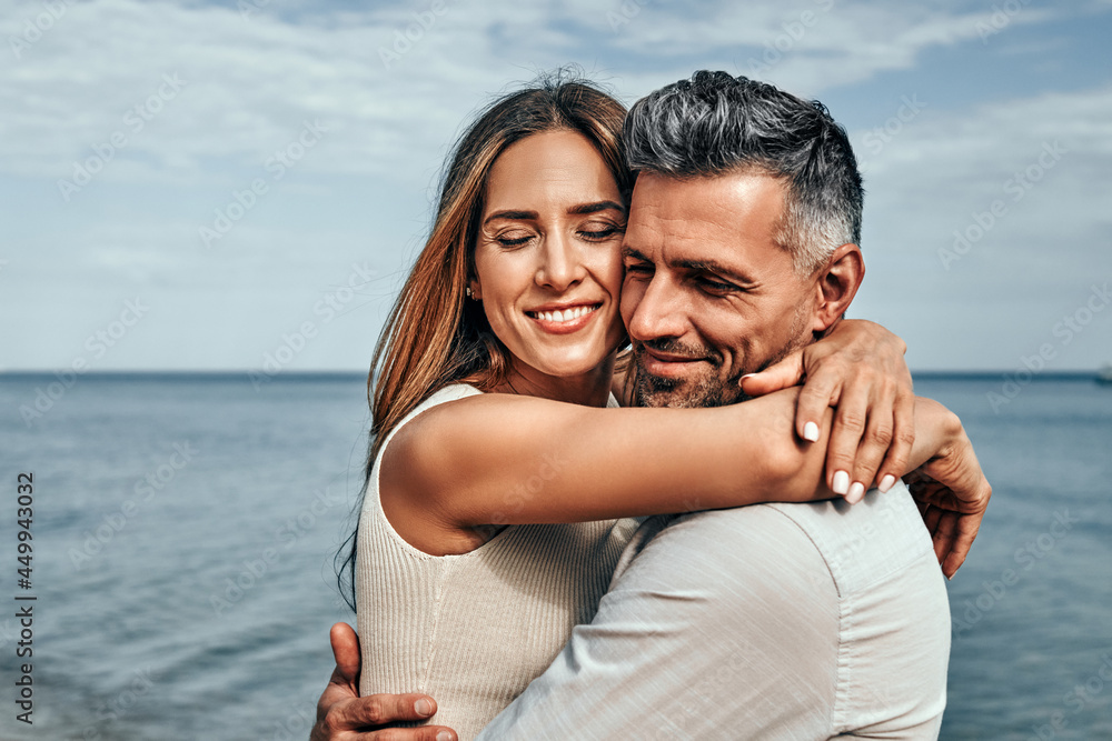 Close up view of a portrait of a handsome couple in love hugging while walking along the beach. Close up view of a portrait of a handsome couple in love hugging while walking along the beach.