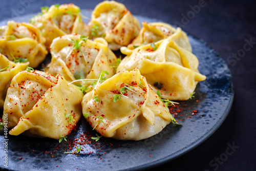 Traditional steamed Kazakh manti garnished with mincemeat and sumah served as close-up on a Nordic design plate