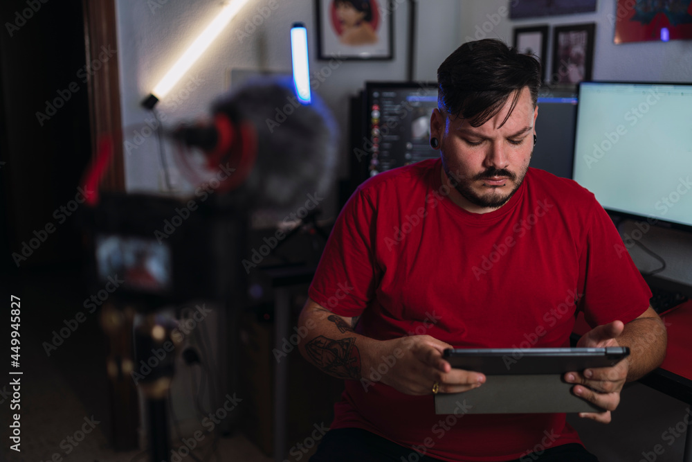 Chico joven gordo con camiseta roja grabando frente a una cámara en un set up gamer