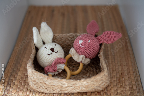 Un conejos de peluche decorativos dentro de una cesta de mimbre en una balda de un armario photo