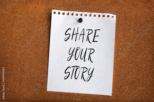 Paper note written with SHARE YOUR STORY inscription on cork board