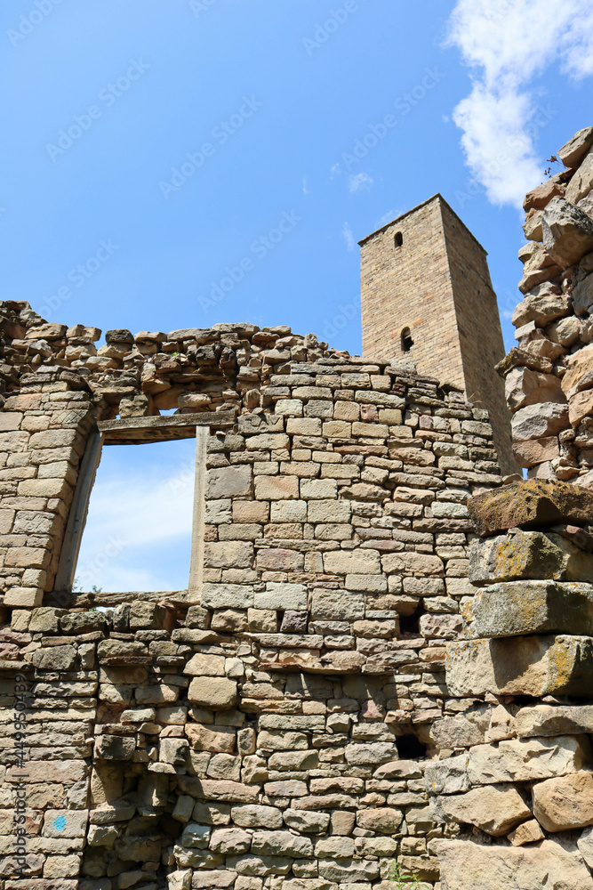 picturesque view of old stone battle tower with the window of ruined house in abandoned village