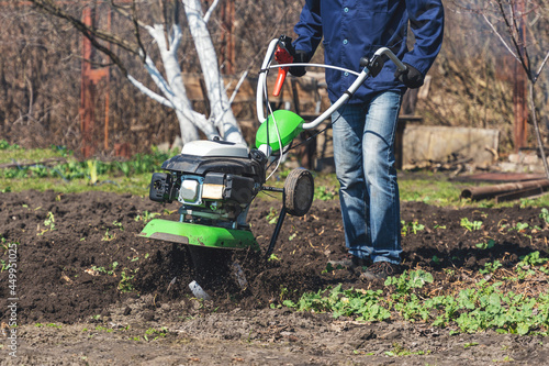 Farmer man plows the land with a cultivator preparing the soil for sowing