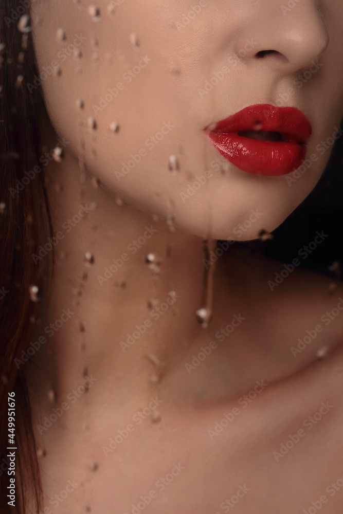 Close up portrait of red lips of woman with cropped head. Drops flowing down the transparent glass. Close up portrait of red lips of woman with cropped head. Drops flowing down the transparent glass.