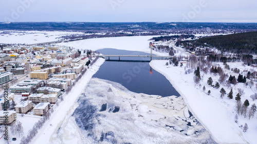 Beautiful winter landscape with buildings and a bridge over Ounasjoki River in Rovaniemi, Finland photo