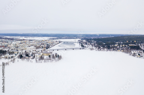 Beautiful winter landscape with buildings and a railway bridge over Ounasjoki River in Rovaniemi photo