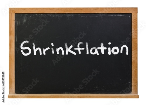 Shrinkflation written in white chalk on a black chalkboard isolated on white photo