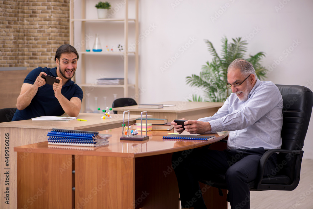 Old male teacher and young male student in the classroom Old male teacher and young male student in the classroom