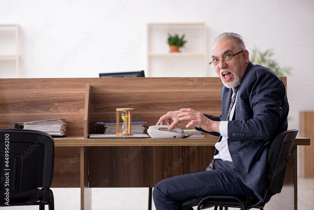 Aged male employee in time management concept Aged male employee in time management concept