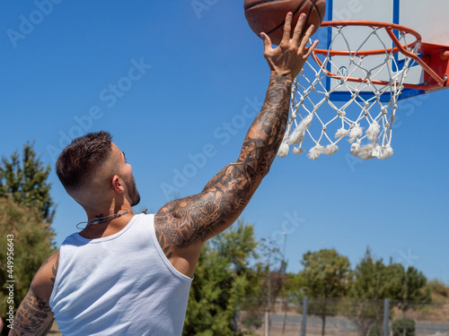 Hombre joven con tatuajes  jugando a baloncesto  photo