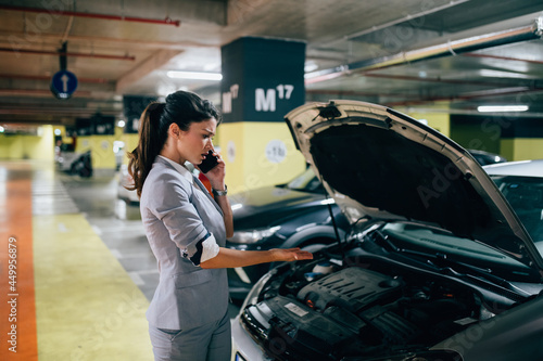 Frustrated and distressed woman has a car failure at public place in underground garage. photo