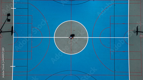 Toma de drone en cancha de baloncesto con un chico en medio de ella  photo