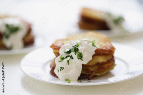 Potato pancakes with sour cream and herbs on plate closeup