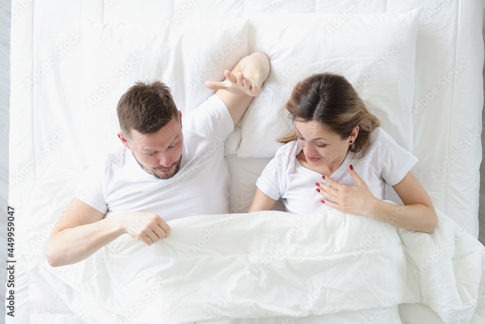 Joyful man and woman looking under blanket while lying in bed Joyful man and woman looking under blanket while lying in bed