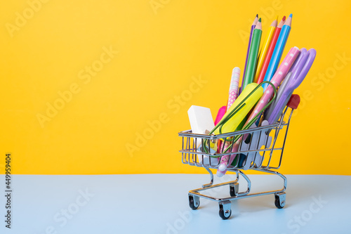 Shopping cart with school supply in front. Back to school concept