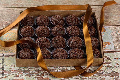 Box with several brigadeiros lined up next to a bow ribbon. Brazilian traditional sweet (side view). photo