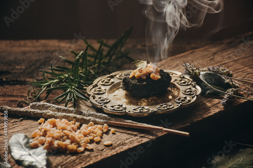 Charcoal burning with incense, incense resin, rosemary, laurel, lavender on a rustic wooden table, 
smudge stick, smudging, energetic cleansing and smoking.Sahumar
