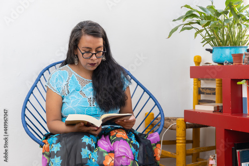 portrait of a mexican young woman wearing tehuana clothes, reading and studying photo